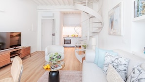 A modern living room with a sofa, coffee table, and TV. A spiral staircase leads to a kitchen area. - Luxury 2 Bedrooms 2 Bathrooms Penthouse, Elevator (Lucca)