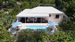 Ein Haus mit überdachter Terrasse, Schwimmbad und Sitzgelegenheiten im Freien.