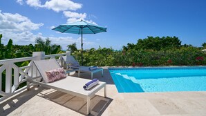 Ein Poolbereich mit Liegestühlen, einem blauen Sonnenschirm und Blick auf den Pool.
