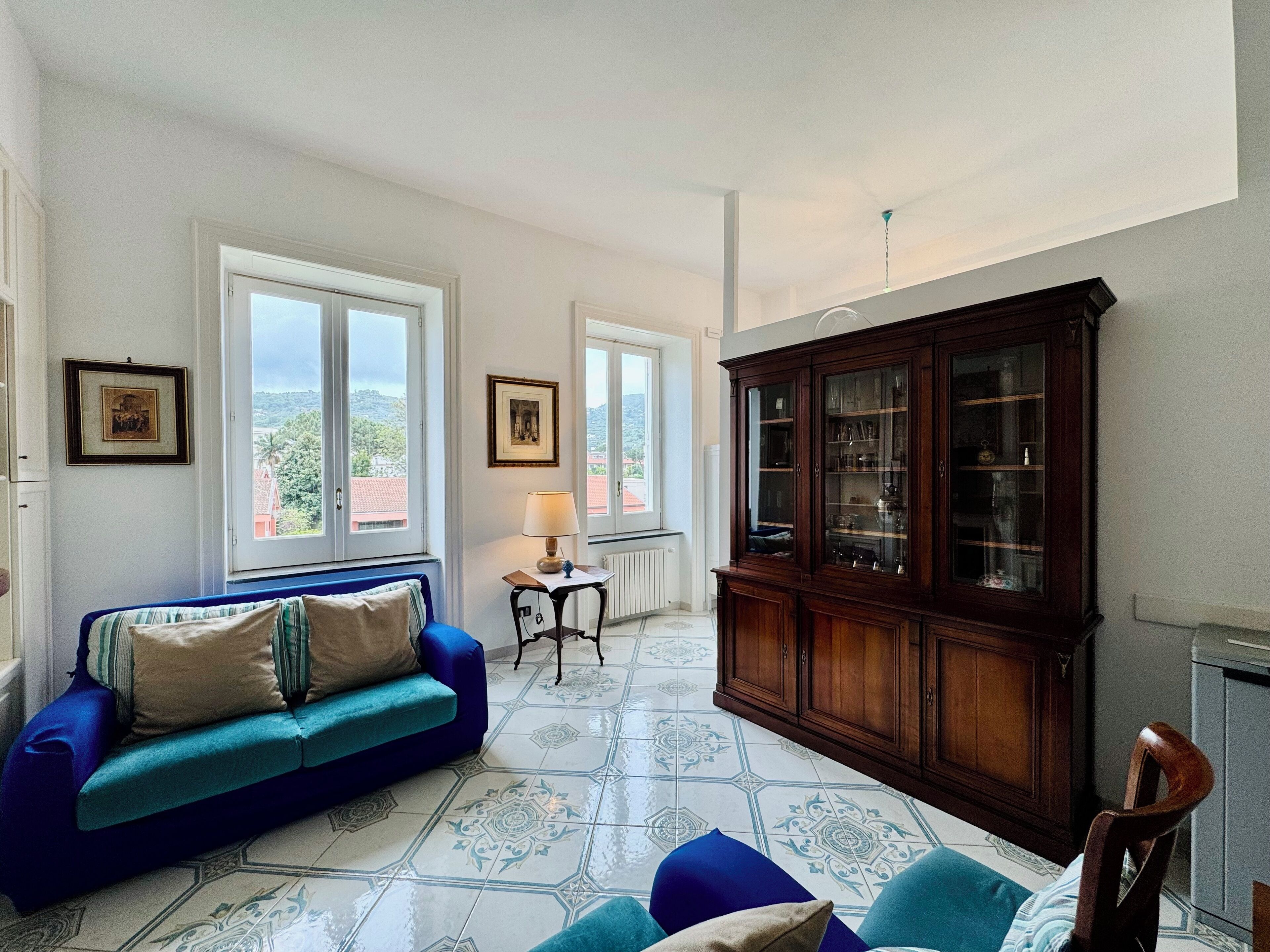 A room with a blue sofa, a wooden cabinet, and patterned floor tiles.