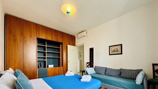 Ein Schlafzimmer mit einem Bett, einer Couch, einem Kleiderschrank und einer Deckenleuchte.