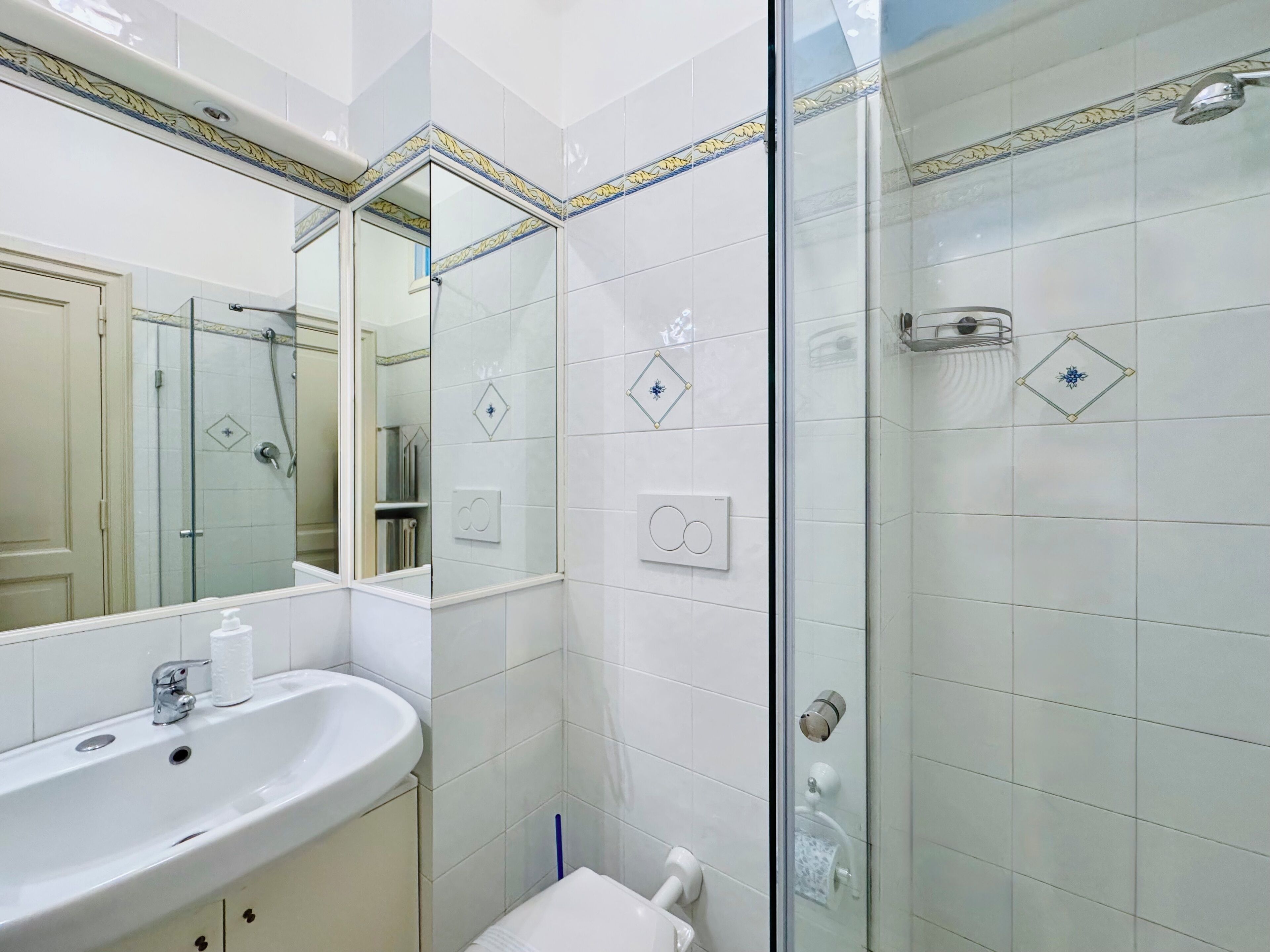 Ein Badezimmer mit einer Duschkabine, einem Waschbecken mit Spiegel und einer Toilette.