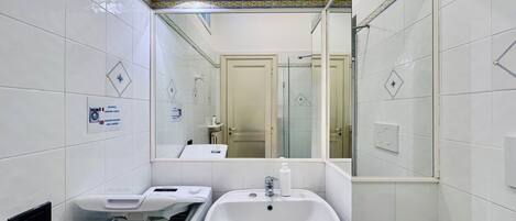 Un baño pequeño con lavadora, lavamanos y espejo.
