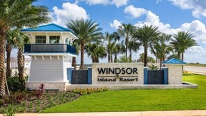 A resort sign with the name "Windsor Island Resort" and a building with a blue roof and white walls.