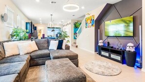 A modern living room with a sectional sofa, a flat-screen TV, and a staircase leading to another level.