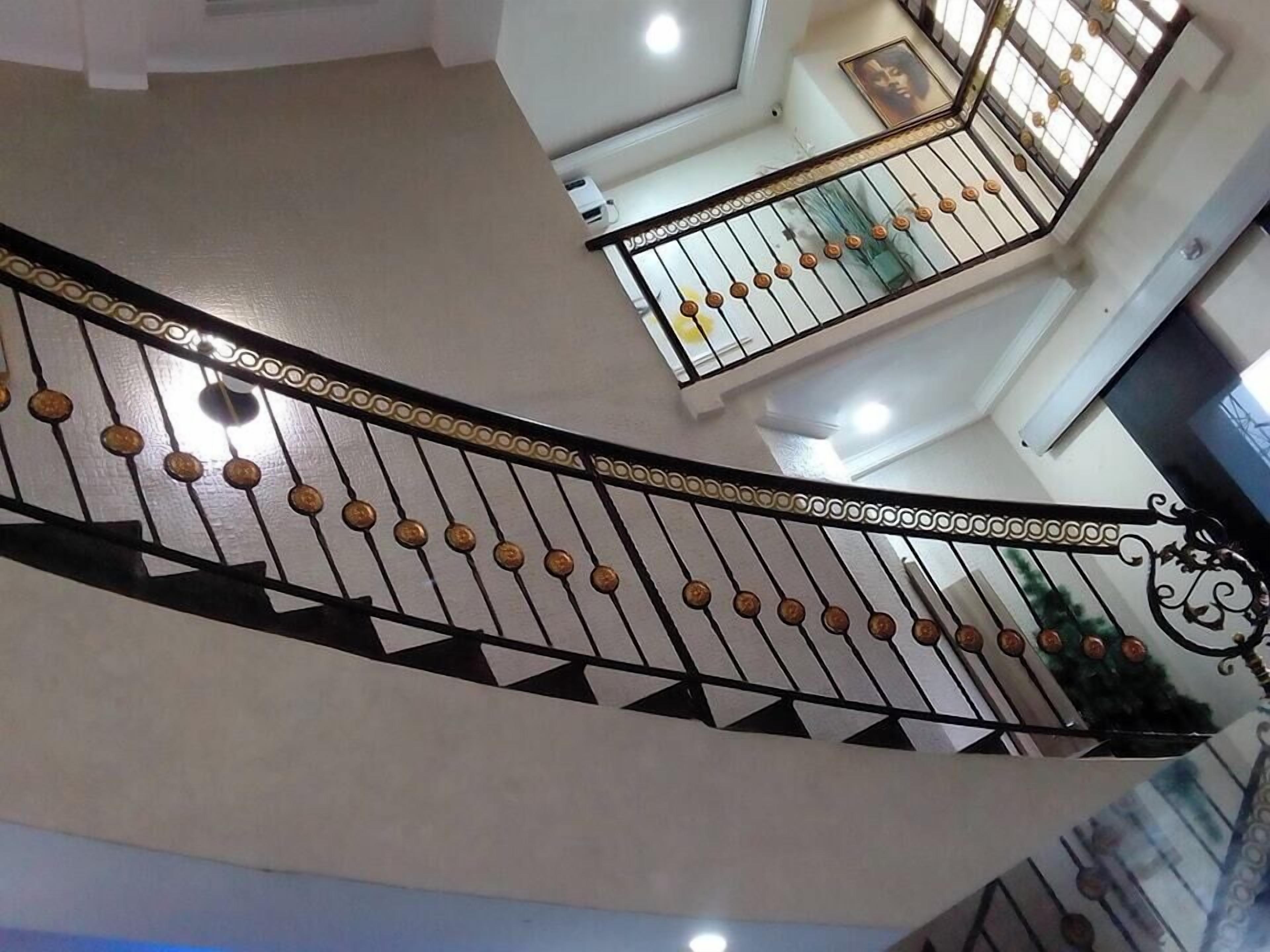 A curved staircase with decorative balusters and a patterned handrail, leading to an upper floor.