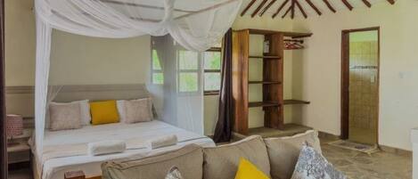 A bedroom with a canopy bed, a sofa, and a wooden shelf.