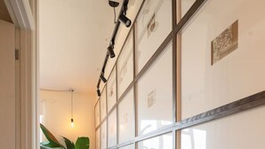 A hallway with a sofa, a plant, and framed pictures on the wall.