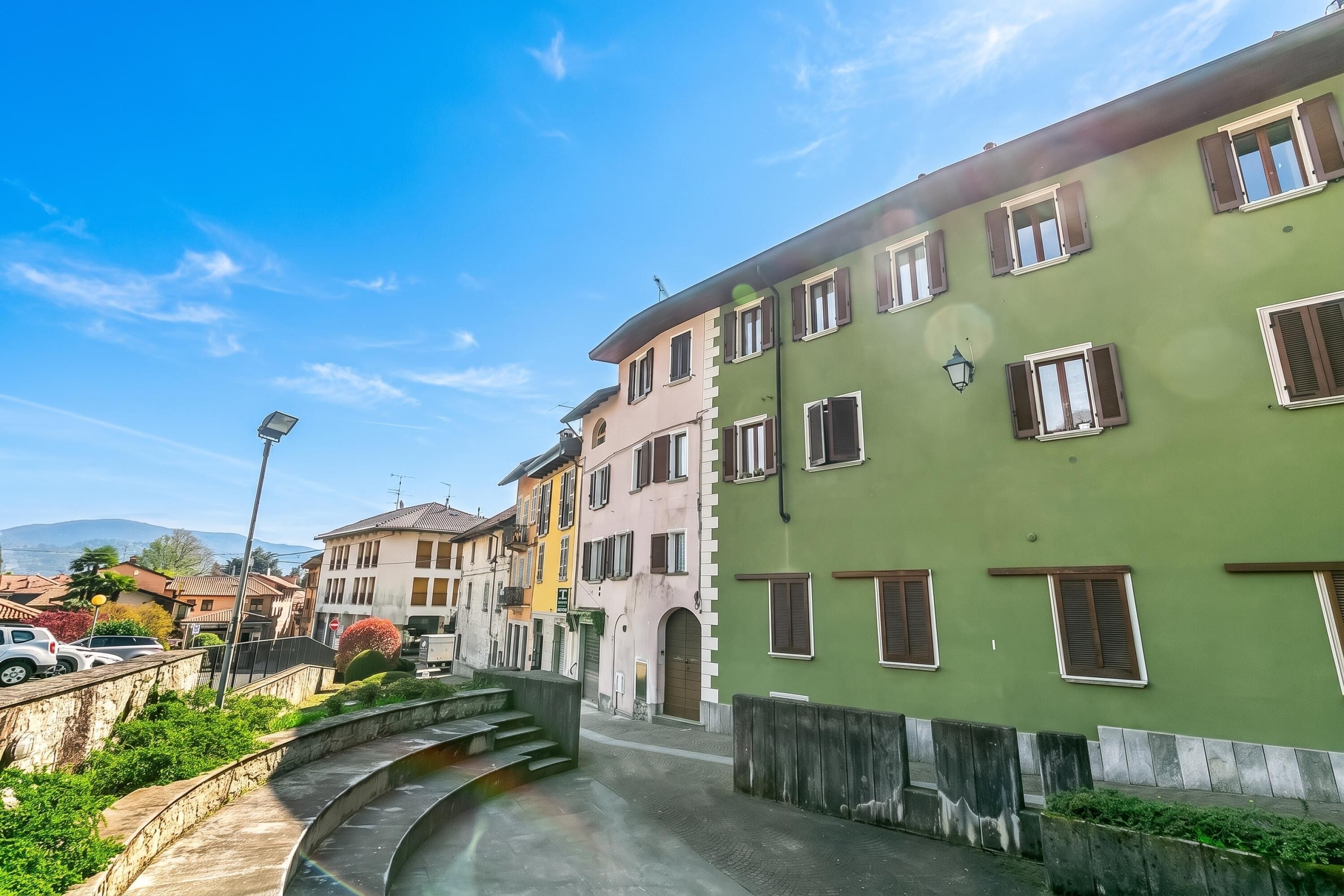 A street with buildings, a curved pathway, and a clear sky.
