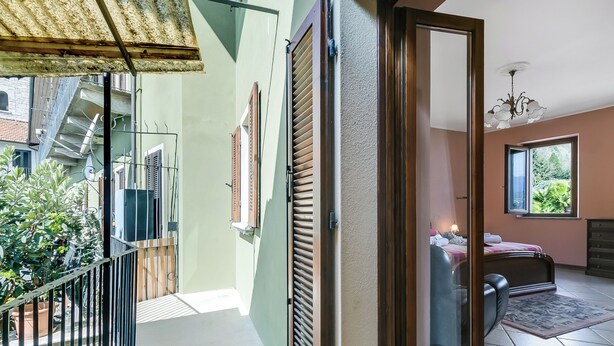 A room with a bed, a window, a door, and a balcony. - Old Pella: 100m to Lake Orta, Terrace and Views (Pella)