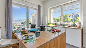 Eine moderne Küche mit einer großen Kochinsel, Blick auf die Stadt und einem Essbereich mit einem Stuhl.