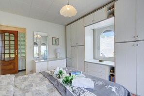 A bedroom with a bed, a dresser, a vanity, and a window.