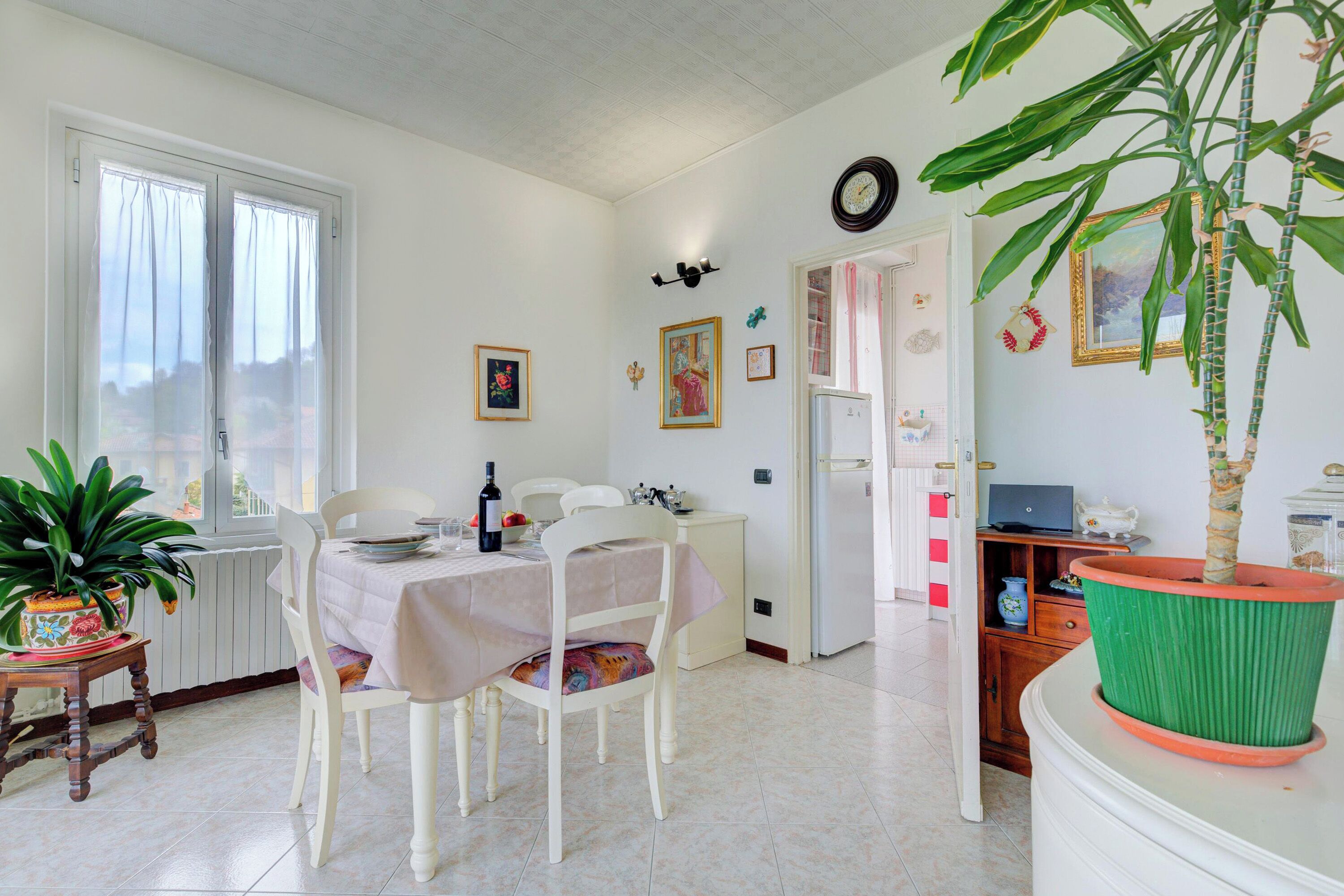 Un coin repas comprenant une table, des chaises, une plante en pot et un réfrigérateur.