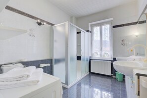 Un baño moderno con cabina de ducha de vidrio, un lavamanos blanco y un espejo grande.