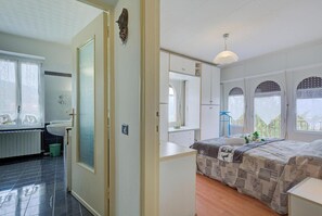 A bedroom with a bed, a window, a mirror, and a door.