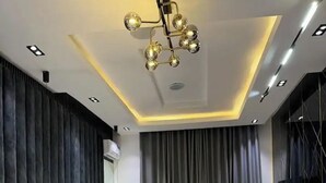 Une chambre moderne avec un grand lit, des rideaux foncés et un luminaire au plafond original.