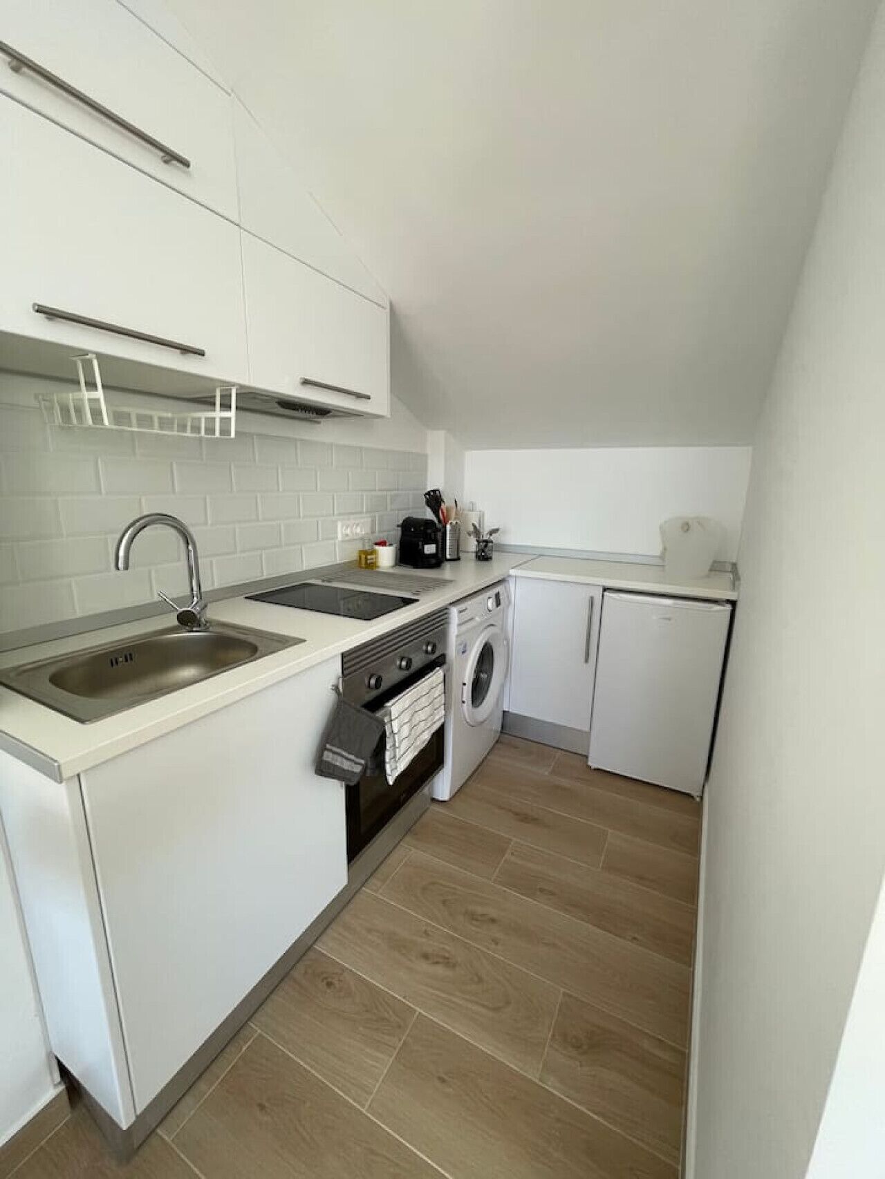 Una cocina compacta con pileta, estufa, horno y lavadora.