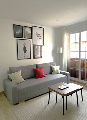 A living room with a grey sofa, a coffee table, and framed pictures on the wall.