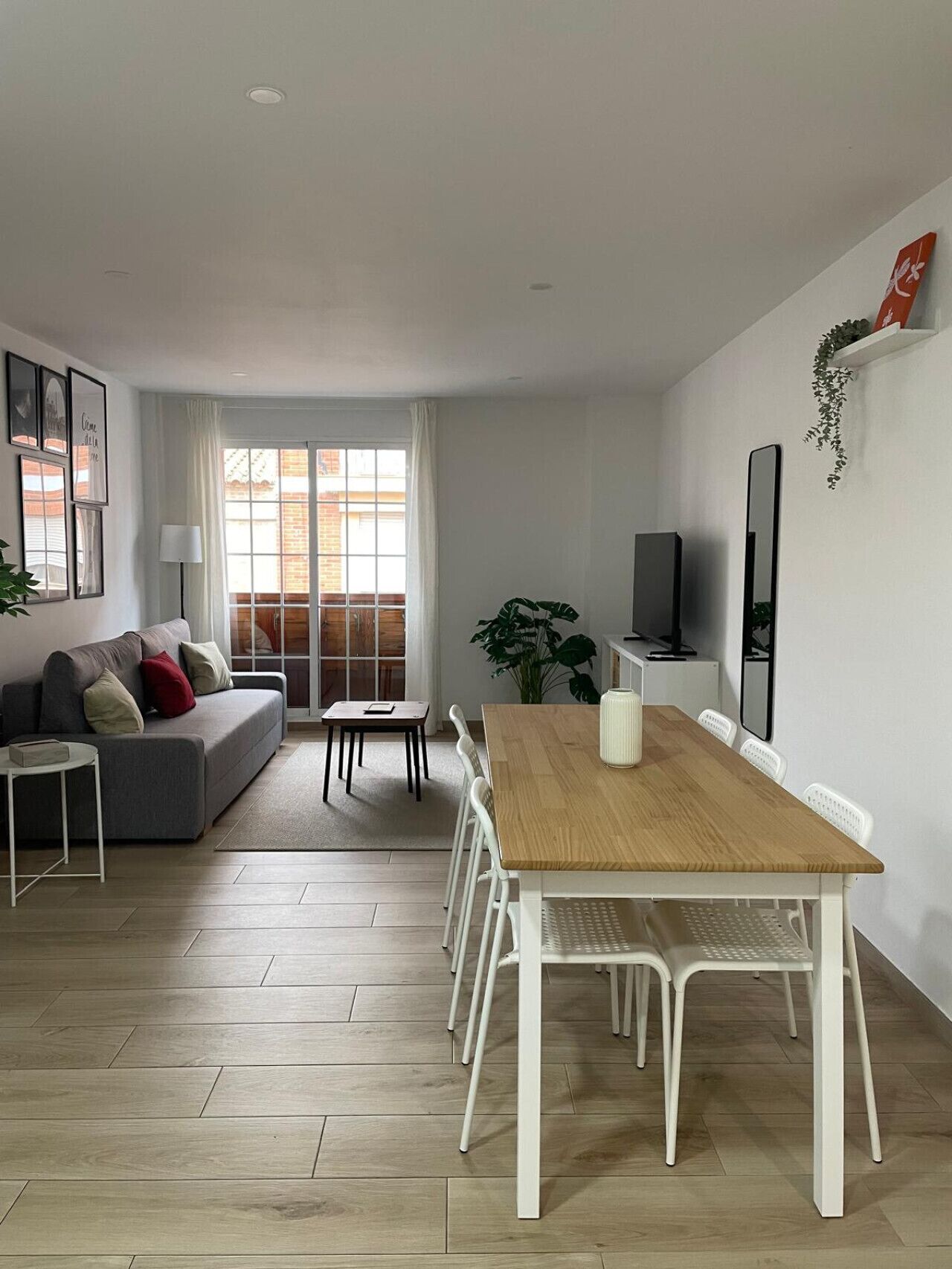 A modern living room with a sofa, dining table, chairs, and a TV.