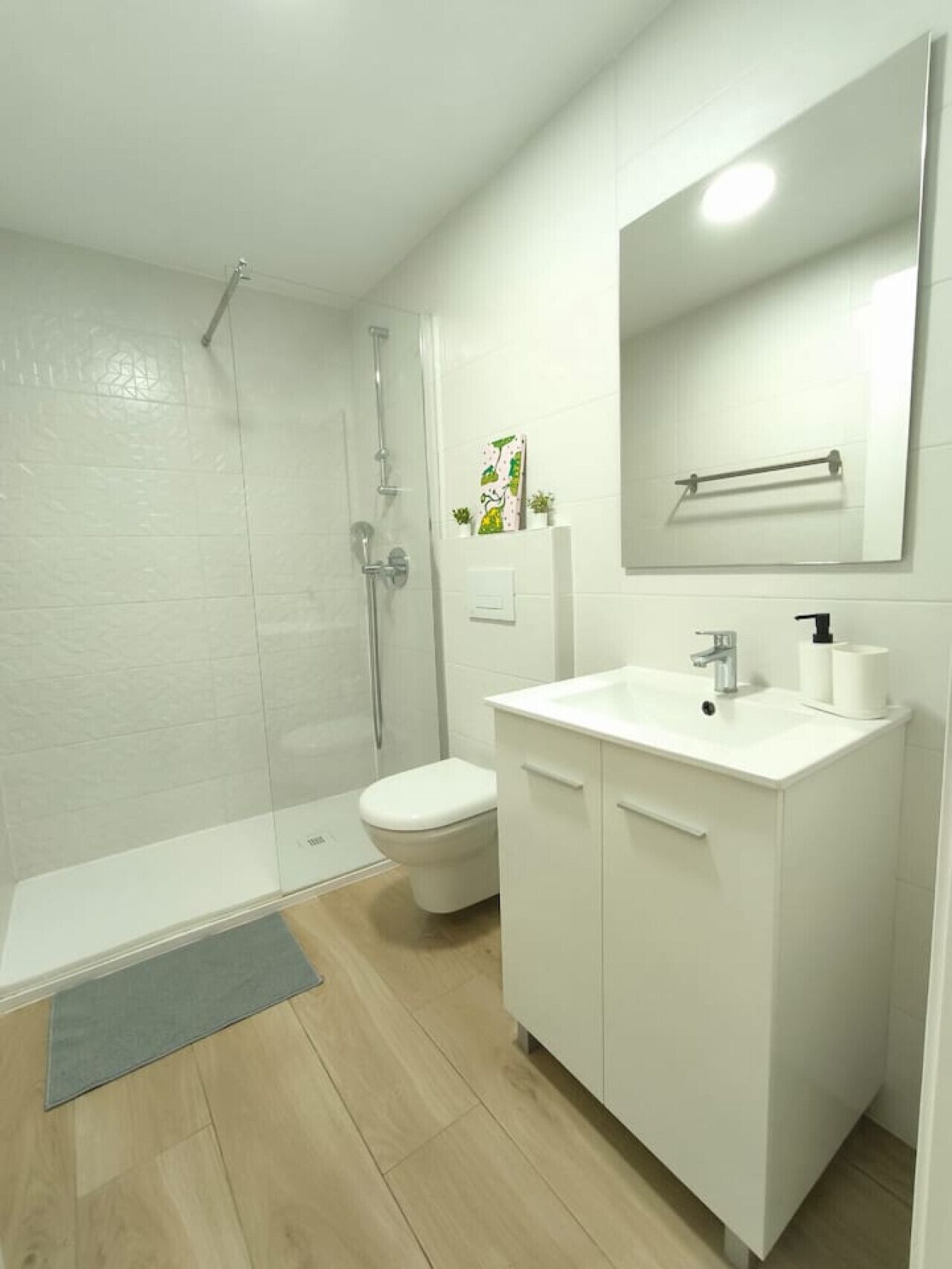 A modern bathroom with a shower, toilet, and sink.
