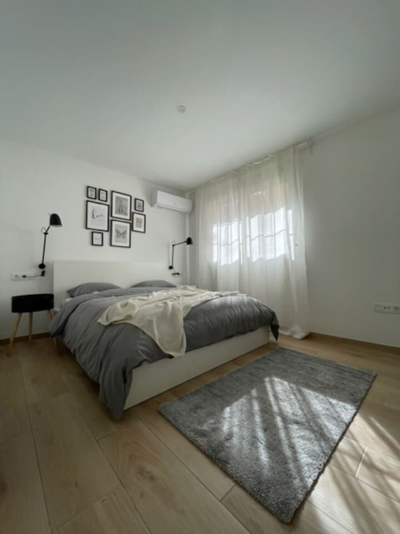 A bedroom with a bed, bedside tables, a rug, and a window with curtains.