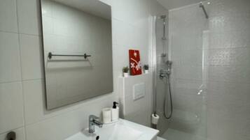 Un baño moderno con un lavamanos, espejo y retrete blancos.