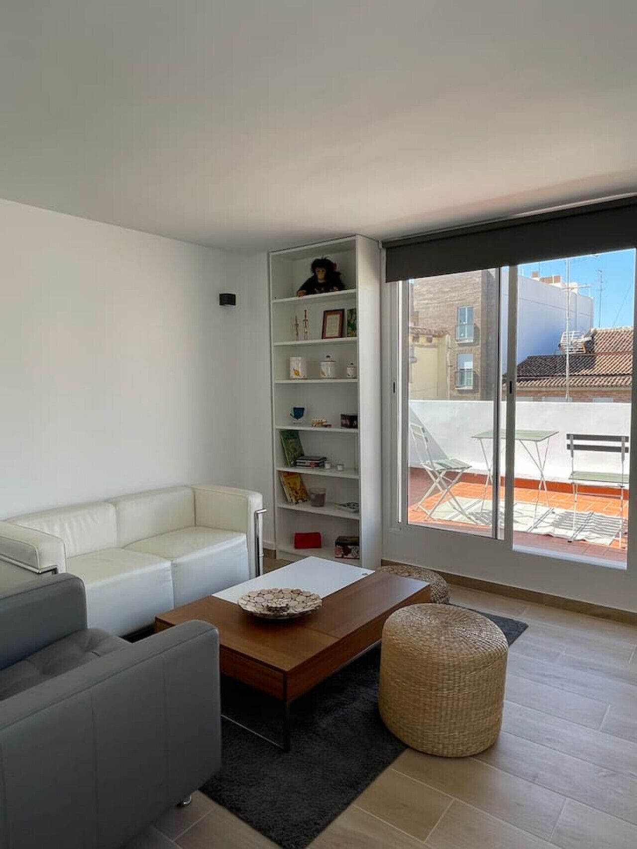 Ein modernes Wohnzimmer mit einem weißen Sofa, einem Holztisch und einem Bücherregal.