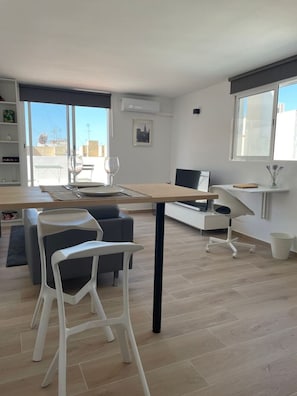 Una sala de estar moderna con comedor, sofá, mesa de centro y televisor.