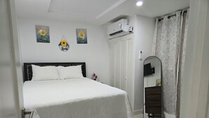 A bedroom with a bed, a wardrobe, a mirror, and an air conditioning unit. - Comfy Fresh and Clean Spacious 1- bedroom apartment with AC in charming Portmore (Portmore)