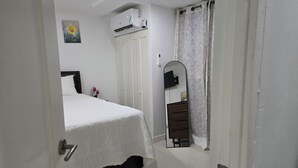 A bedroom with a bed, a wardrobe, a mirror, and a ceiling fan. - Comfy Fresh and Clean Spacious 1- bedroom apartment with AC in charming Portmore (Portmore)