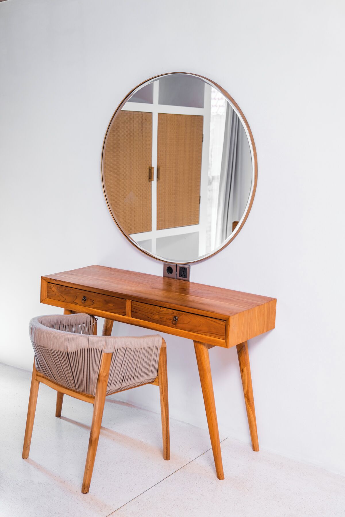 Un tocador de madera con un espejo redondo, una silla y una c ómoda.