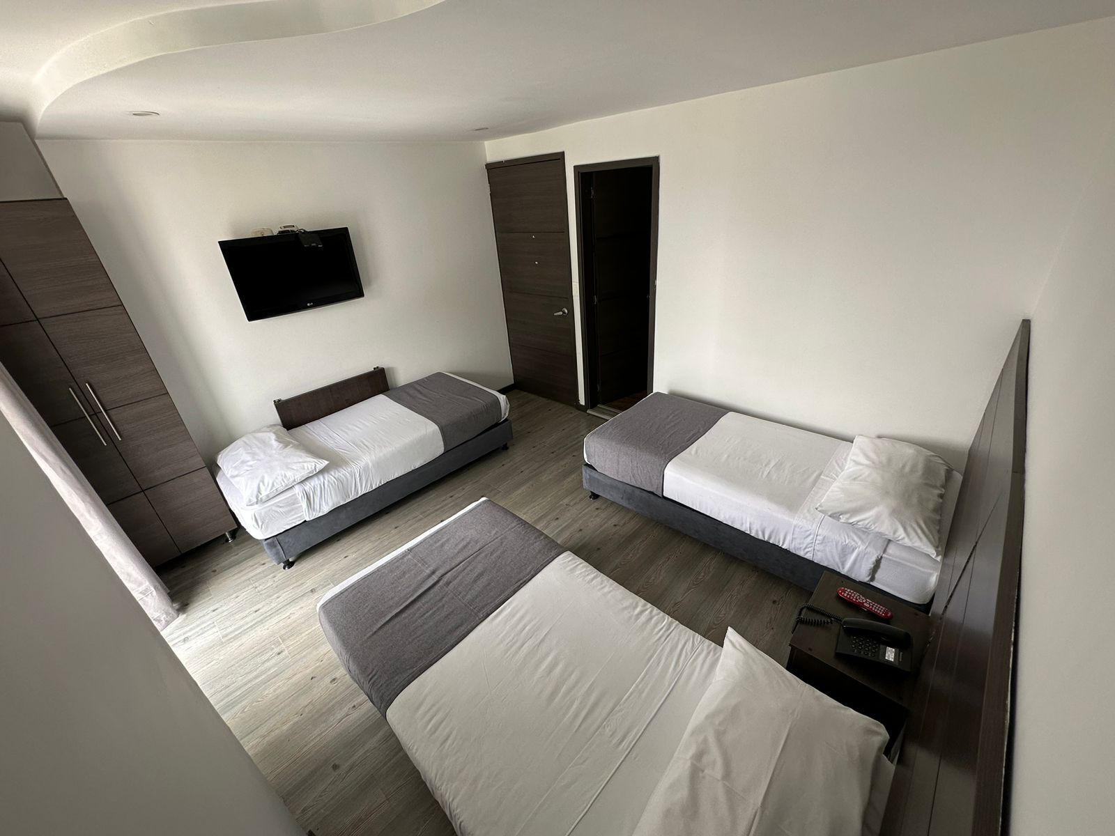 Une chambre d’hôtel moderne équipée de deux lits simples, d’une armoire, d’une télévision et d’une porte donnant accès à la salle de bain.