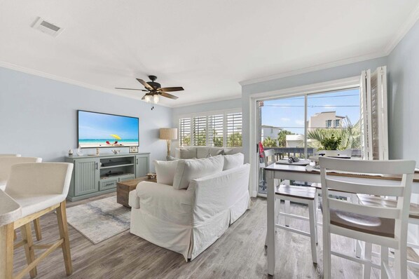 A living room with a sofa, TV, and dining area with chairs and a table.