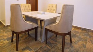A dining area with a rectangular table and four upholstered chairs. - Emsworth Hotels and Apartments  (Abuja)