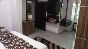A bedroom with a bed, a wardrobe, a mirror, and a television. - Emsworth Hotels and Apartments  (Abuja)