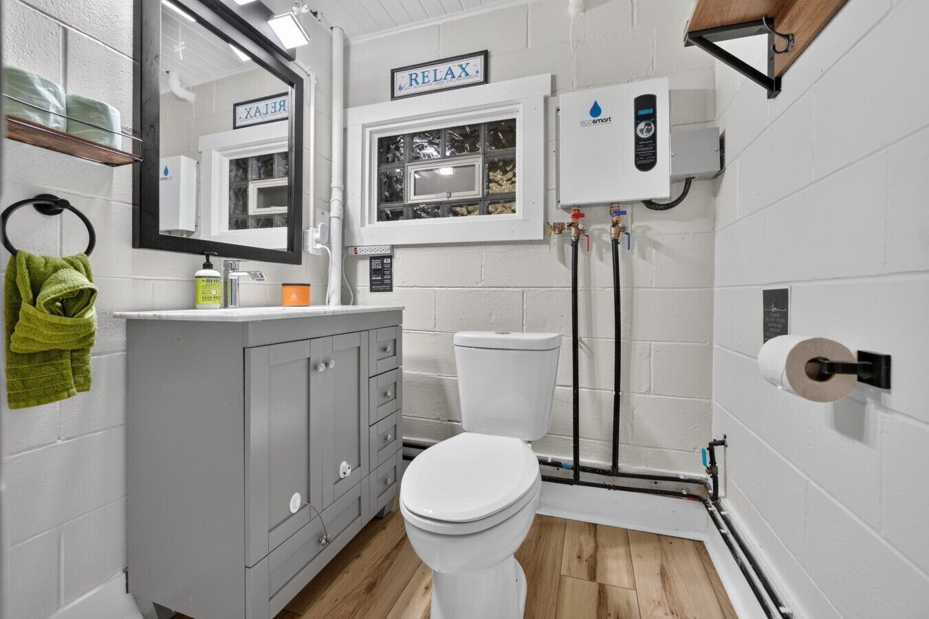 Une petite salle de bain comprenant des toilettes, un lavabo, un miroir et un porte-serviettes.