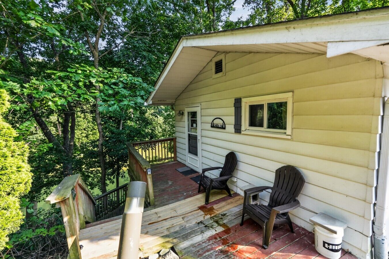 A wooden cabin with a porch, two chairs, and a small window.