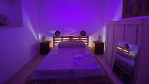 Ein Schlafzimmer mit Bett, Nachttischen, einem Kleiderschrank und einer Deckenleuchte.