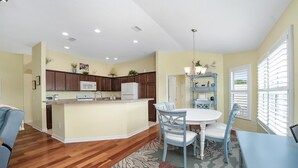 A modern kitchen with wooden cabinets, a white refrigerator, and a built-in microwave. - Charming Courtyard Villa - 3-bedroom house with AC in The Villages (The Villages)