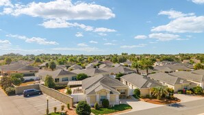A residential area with multiple houses, a parking lot, and a clear sky. - Charming Courtyard Villa - 3-bedroom house with AC in The Villages (The Villages)