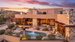 A modern house with a pool, outdoor seating, and a patio area.