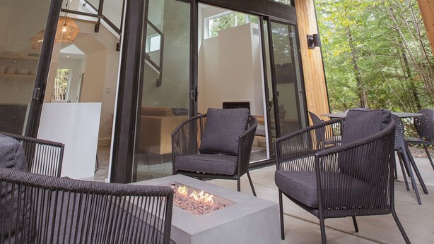 Eine moderne Außenpatio mit Holzboden, großen Glasfenstern und schwarzer Rattanmöbel.