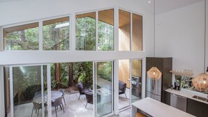 Eine moderne Küche mit einer großen Kochinsel, einem Essbereich mit rundem Tisch und Stühlen sowie einer verglasten Terrasse mit Grill.