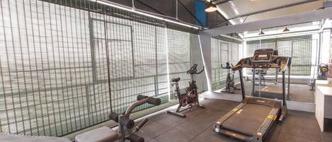 A gym with exercise equipment including a treadmill, stationary bike, and weight machines.