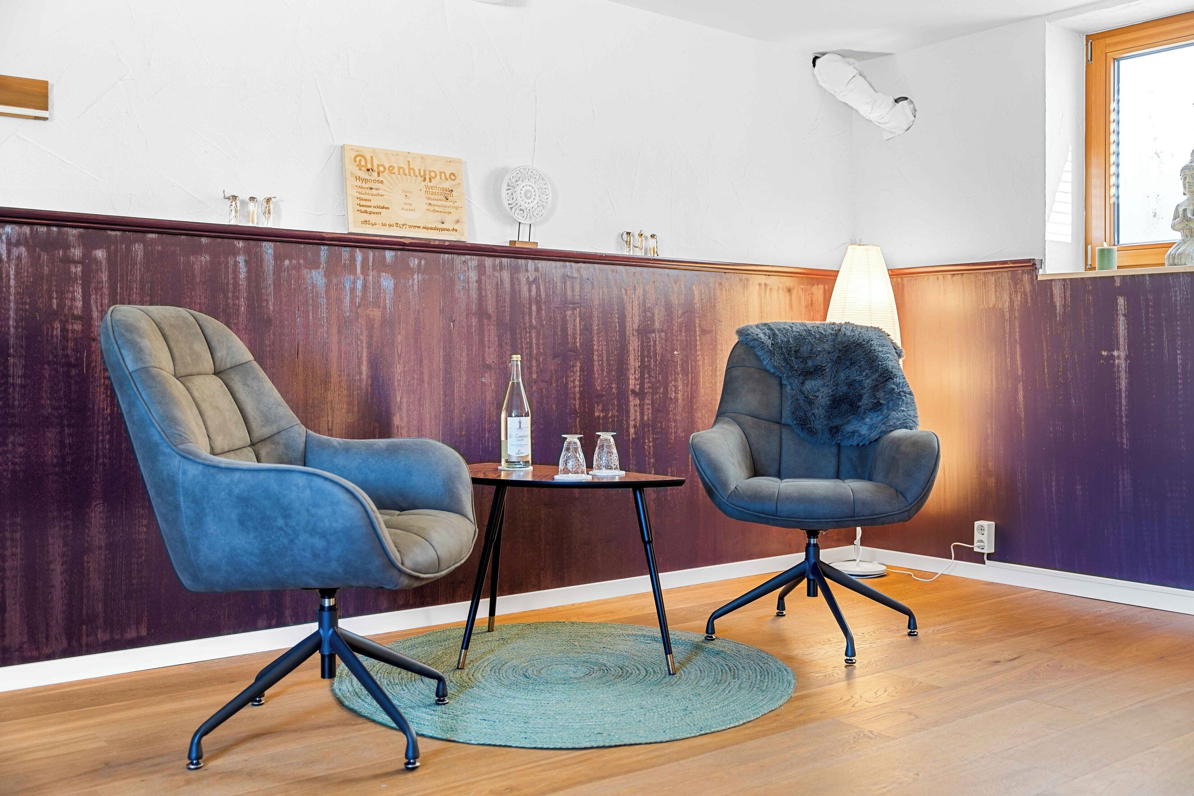 A room with two chairs, a small table, and a lamp.