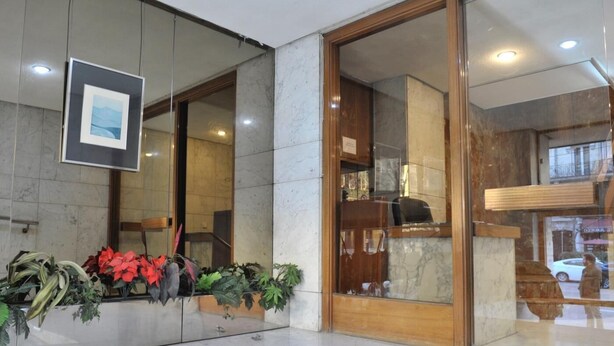 A reception area with a marble floor, a reception desk, and potted plants. - Goya - 1 Bedroom Apartment (Madrid)