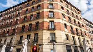 Un edificio en esquina con varios balcones, un letrero que dice 'SUPER BAZAR' y un letrero que indica 'Calle Sandoval'.