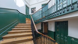 Eine Holztreppe mit grünen Wänden und Türen, die zu einer oberen Etage führt.