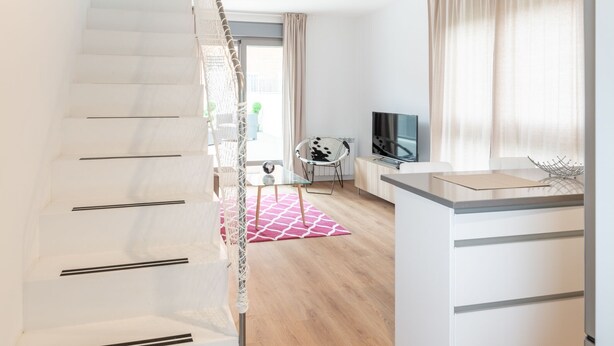 Un apartamento moderno con una escalera, una zona de cocina y un espacio de sala.