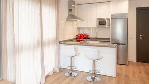 A modern kitchen with a central island, stainless steel appliances, and white bar stools.